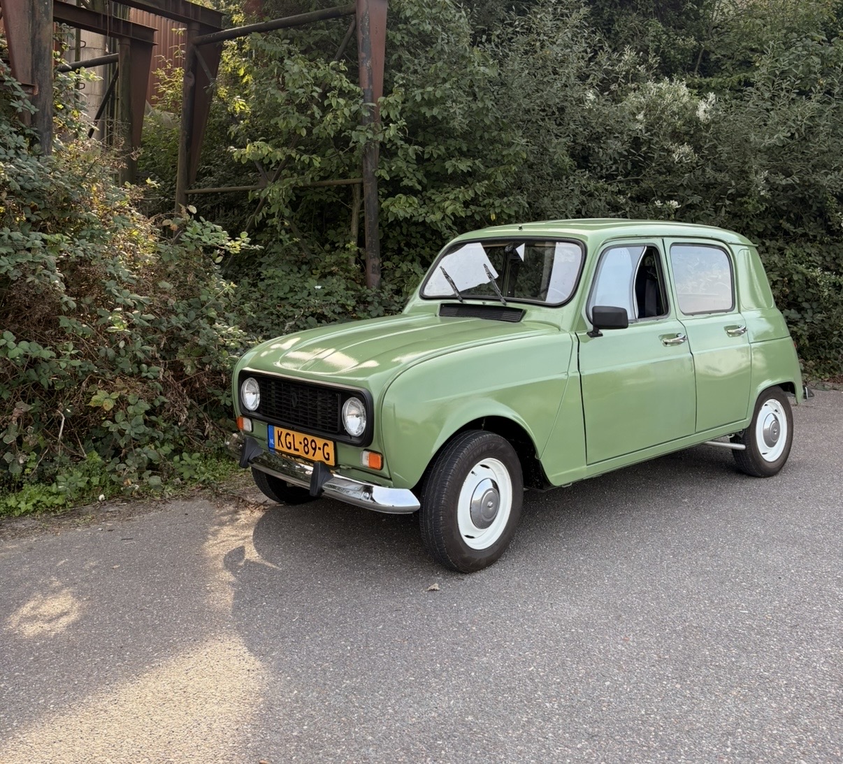 Groene klassieke Renault 4 langs een groene, landelijke weg